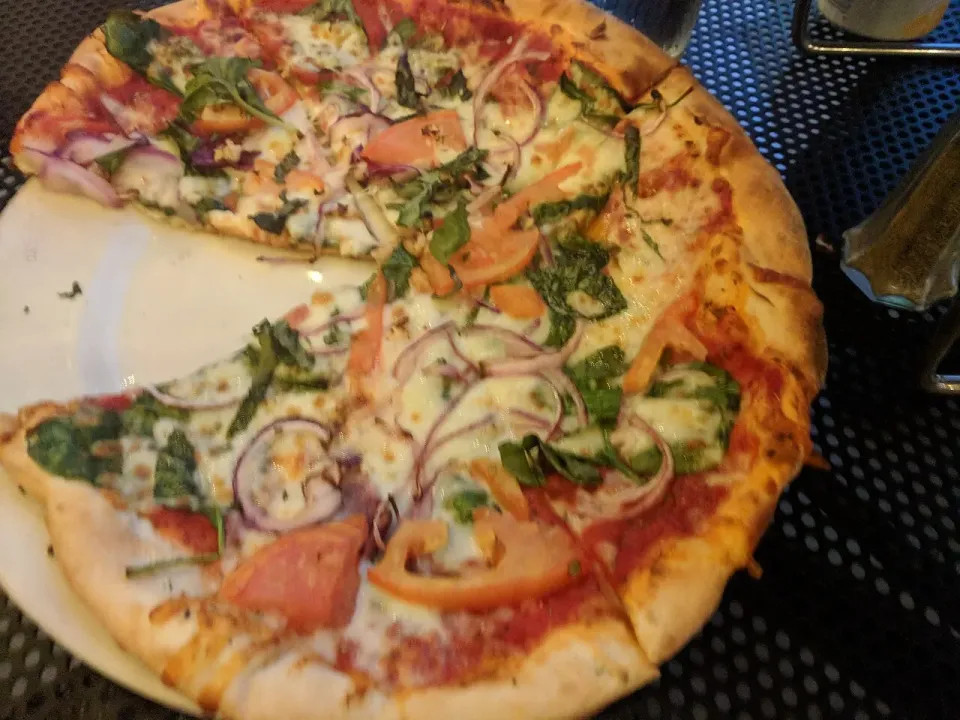 Pizza con tomate, cebolla morada, espinaca y mozzarella