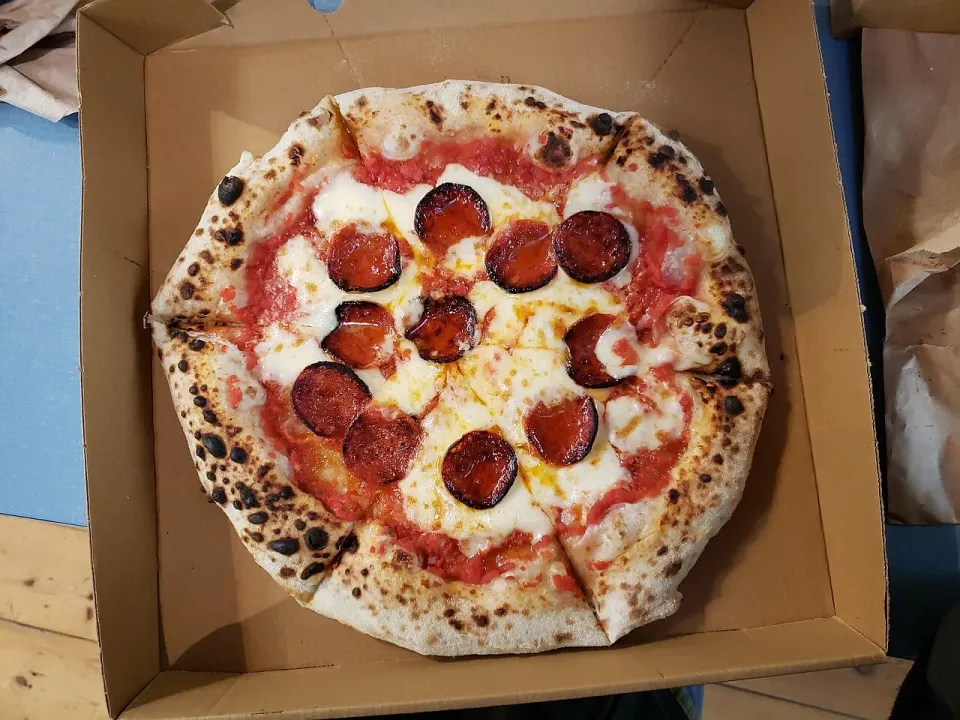 Pizza con rodajas de salami en caja para llevar